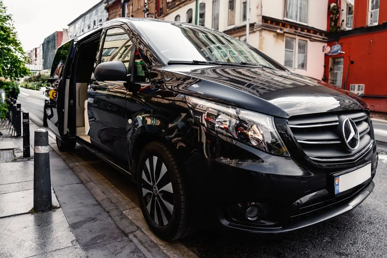 services-04 A stylish black Mercedes-Benz van parked on a bustling city street, showcasing luxury and modern design.