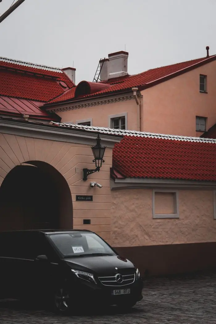 services-02 Scenic urban view featuring buildings with red roofs and a Mercedes van parked on a cobblestone street.