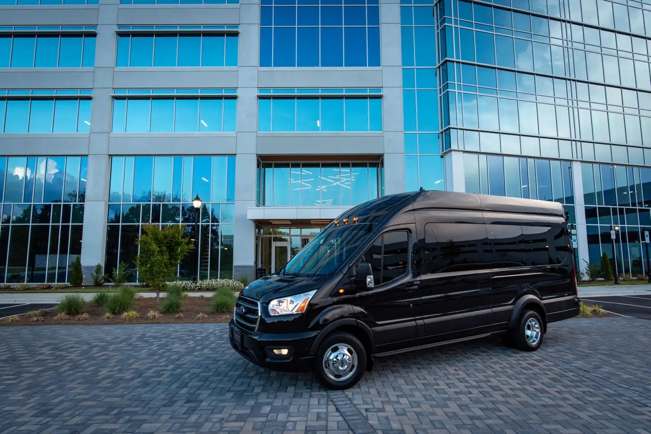 services-img Black luxury van parked in front of a modern office building under daylight.